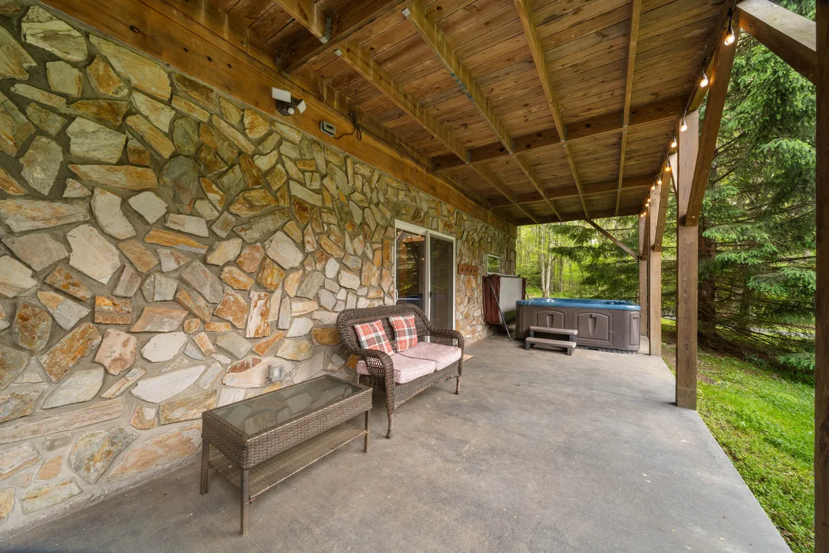 This photo captures a tranquil outdoor seating area with a bubbling hot tub set against a backdrop of surrounding greenery and a low stone wall. The scene exudes privacy and relaxation, perfect for soaking under the stars or enjoying a quiet morning surrounded by nature.