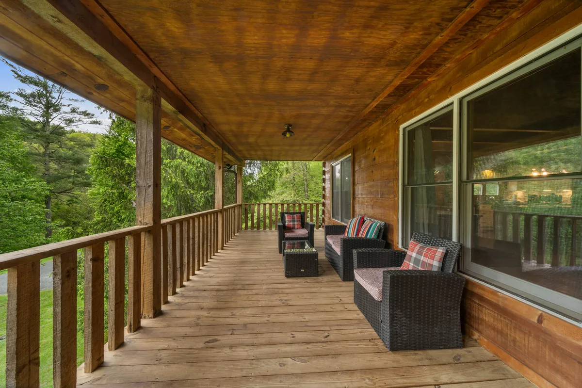 An inviting deck with comfortable outdoor seating overlooks natural greenery, framed by a wooden railing. The setting is ideal for couples to enjoy morning coffee, read together, or share a glass of wine while taking in the peaceful views.