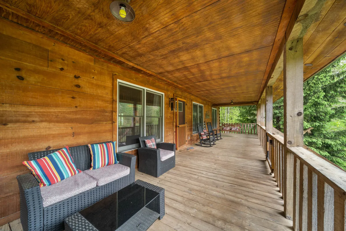 A cozy outdoor seating area with decorative cushions and a wooden railing, overlooking lush greenery. The space is perfect for family members or friends to relax, enjoy morning coffee, or share stories in the tranquil mountain setting.